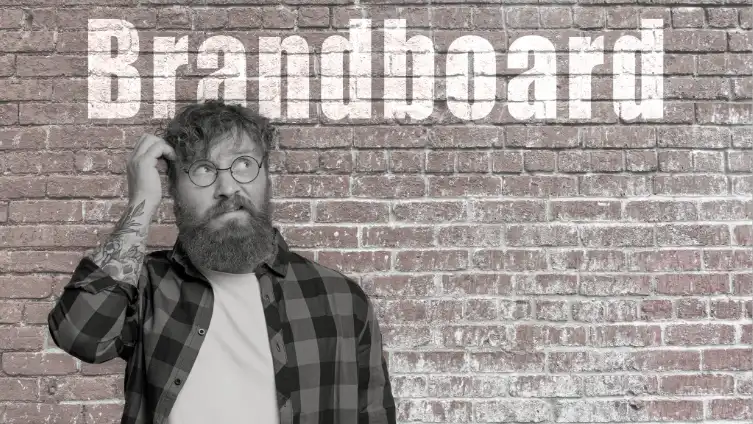 Homme se grattant la t&ecirc;te devant le mot brandboard sur un mur, illustrant des conseils en communication pour d&eacute;finir son identit&eacute; visuelle.